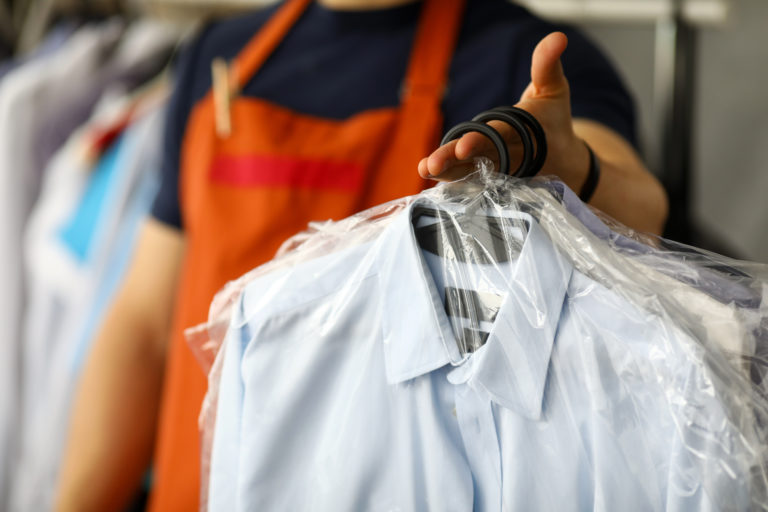 Clothes dry cleaning service worker returning shirts to customer close-up